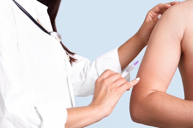 close-up-shot-female-doctor-s-hands-makes-vacciantion-patient-uses-syringe-inject-upper-arm-prevents-serious-disease-isolated-blue-wall-selective-focus-heathcare-concept_176532-6503
